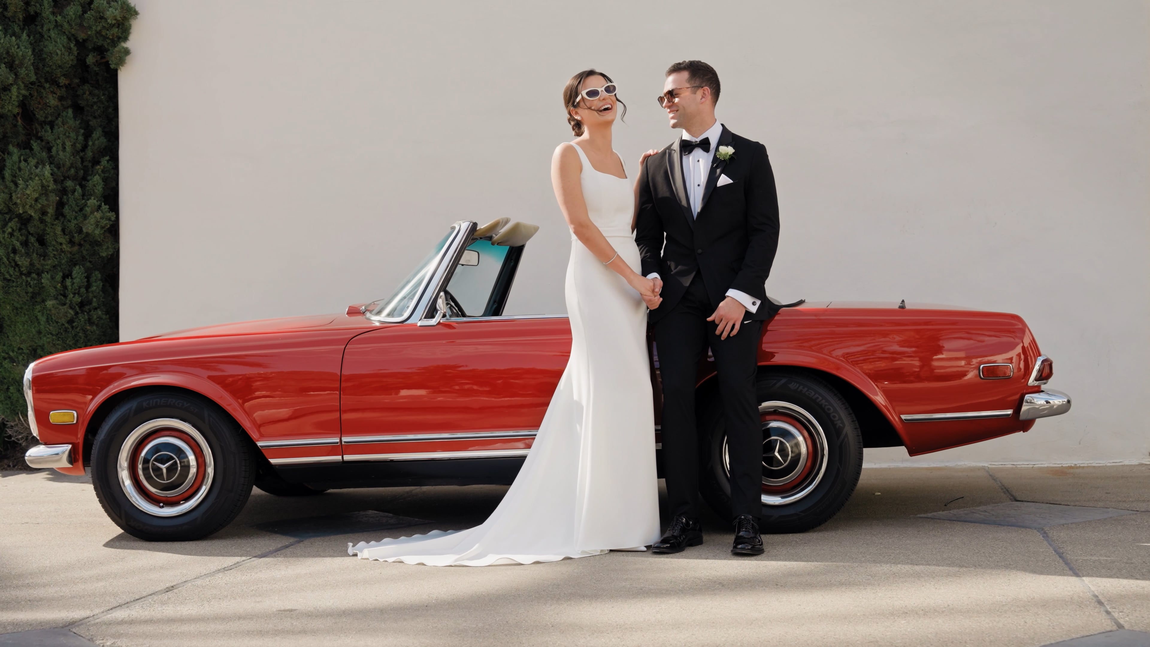 Wedding couple beside a red vintage car