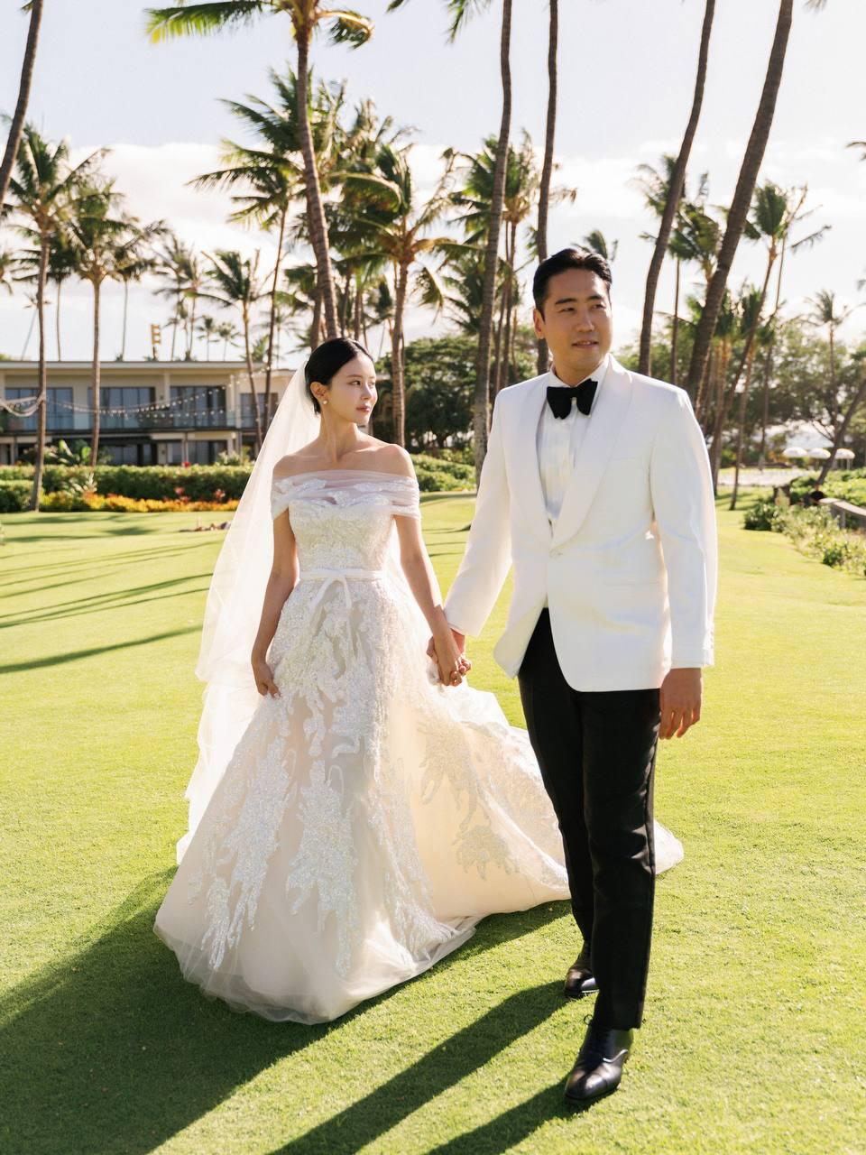 Wedding couple walking under palms by Aster Films