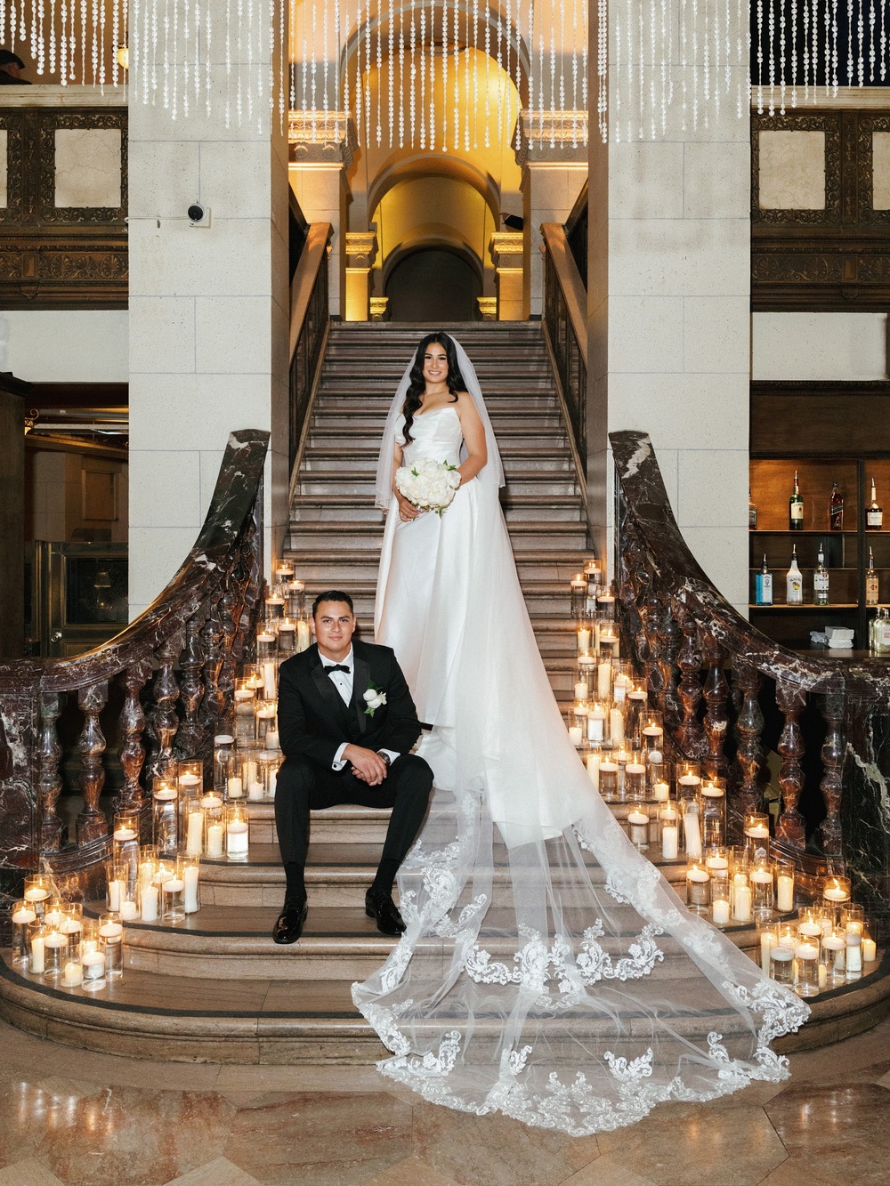 Bride and groom on a candlelit marble staircase in an elegant interior