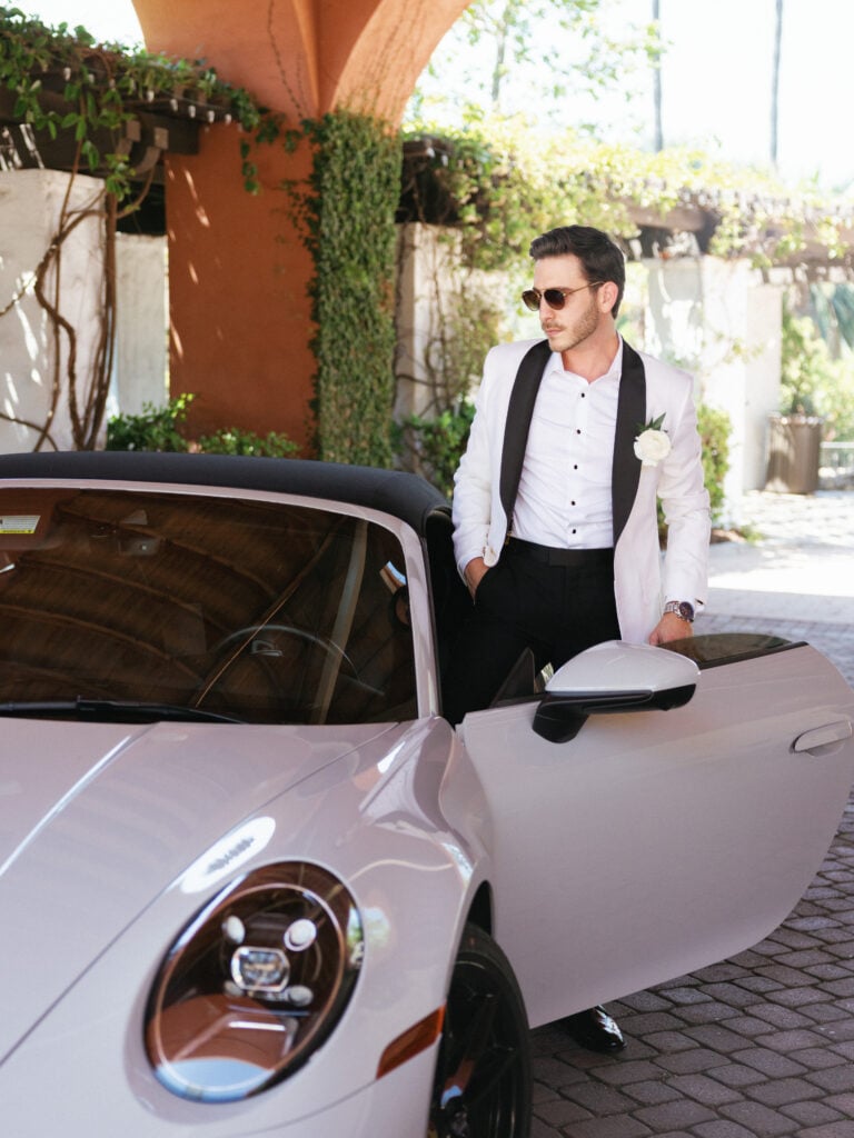 Editorial groom portrait with a Porsche convertible to showcase full-day wedding coverage hours and timeline planning.