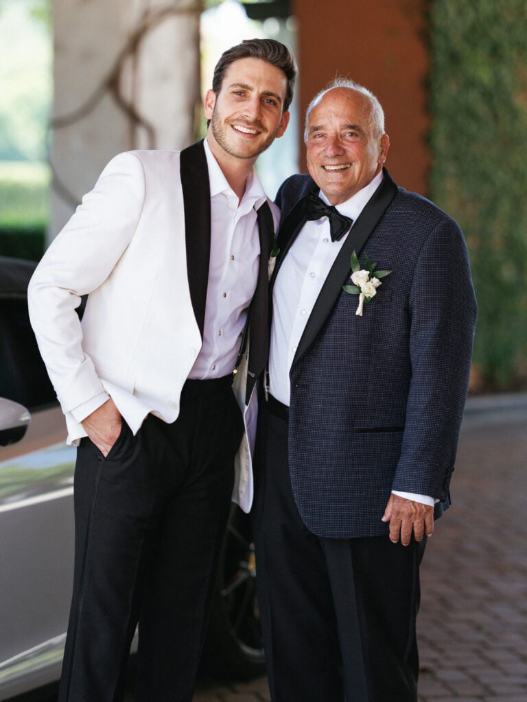 Groom and father wearing black-tie attire captured during early wedding coverage hours at a luxury estate.