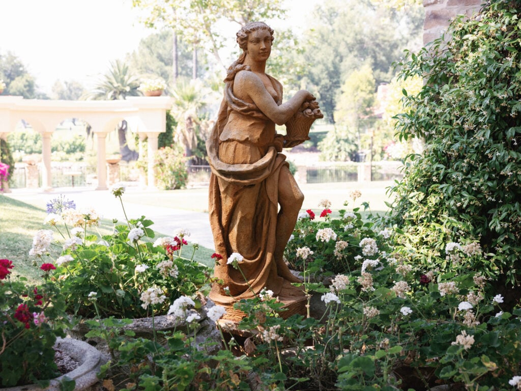 Antique stone statue in a lush garden setting at the European-inspired Hummingbird Nest Ranch wedding venue in California.