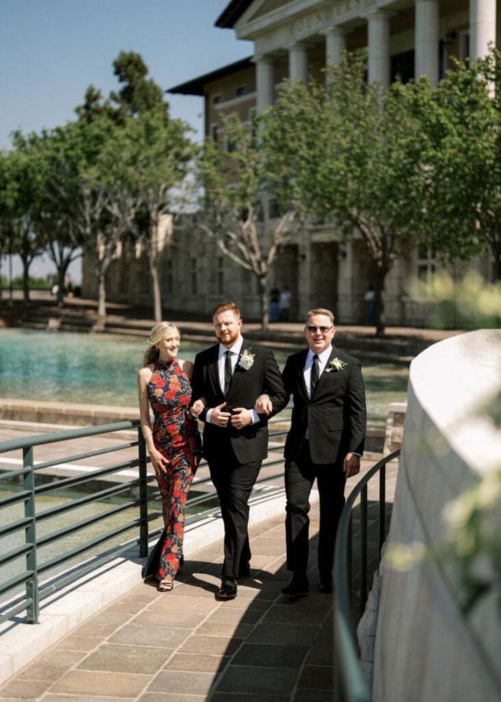 Sun-drenched family wedding processional by the water at Soka University of America during peak daylight hours.