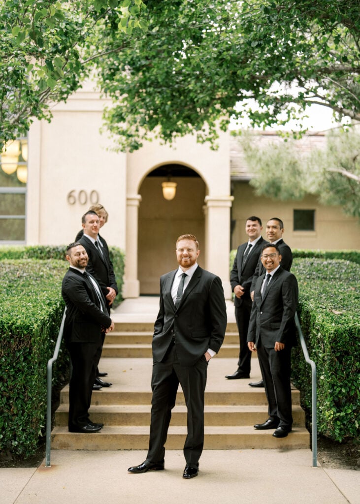 Sharp black-tie groomsmen style captured in natural open shade to avoid harsh overhead midday sun.