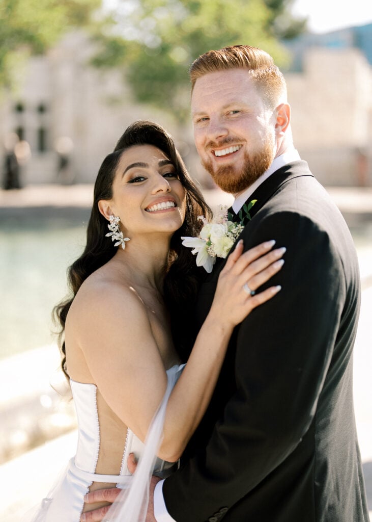 Radiant bride and groom close-up portrait showcasing Hollywood waves and statement bridal earrings in flattering light for luxury wedding venue photography.