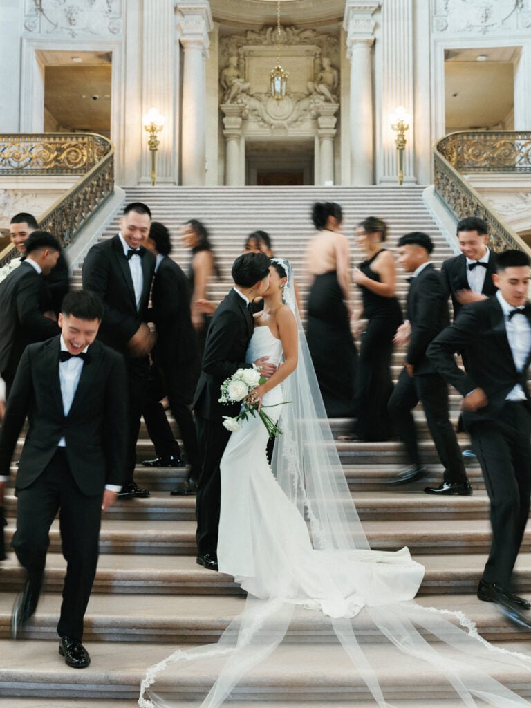 Editorial motion blur wedding portrait of a bride and groom kissing on a grand staircase at San Francisco City Hall.