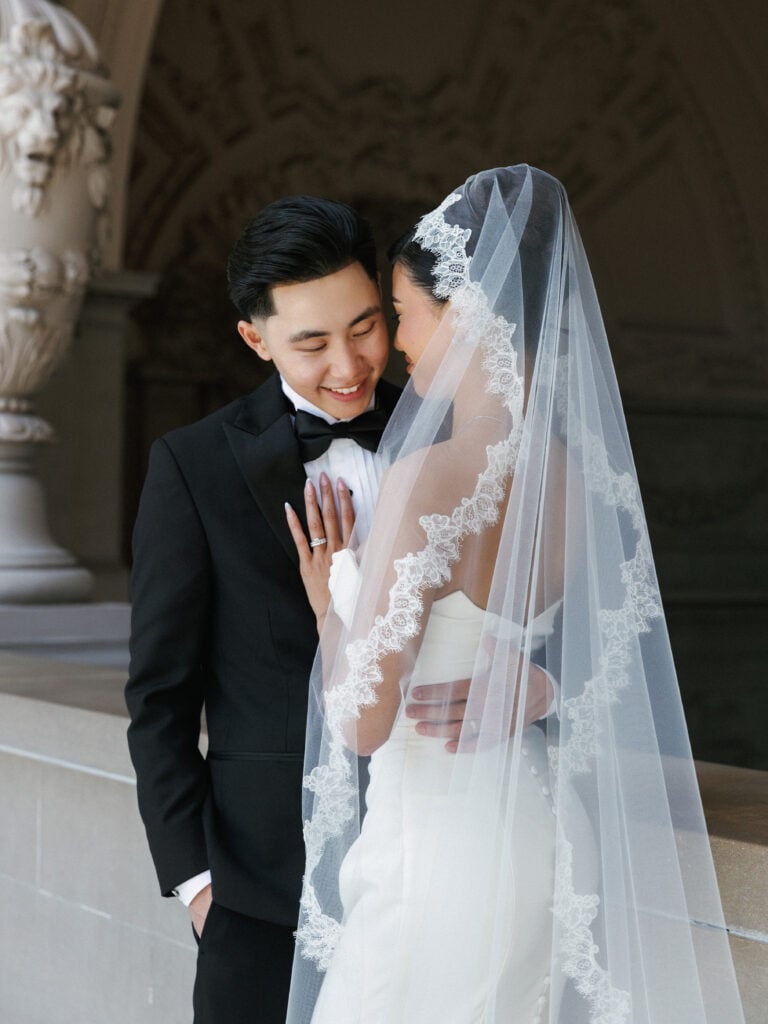 Intimate newlywed embrace in an architectural archway, utilizing diffuse indoor light for timeless wedding venue photography.