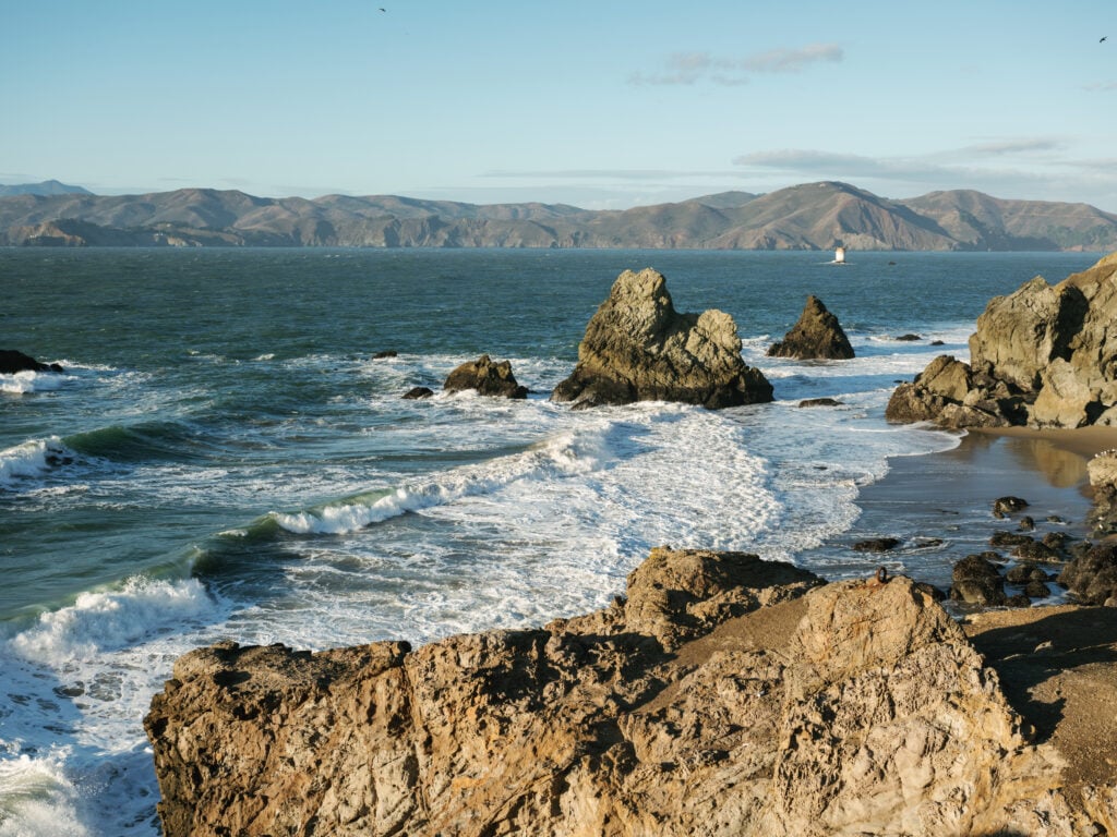 Dramatic ocean cliffs and crashing waves at Lands End in San Francisco, inspiring natural light backdrops for high-end wedding venue photography.