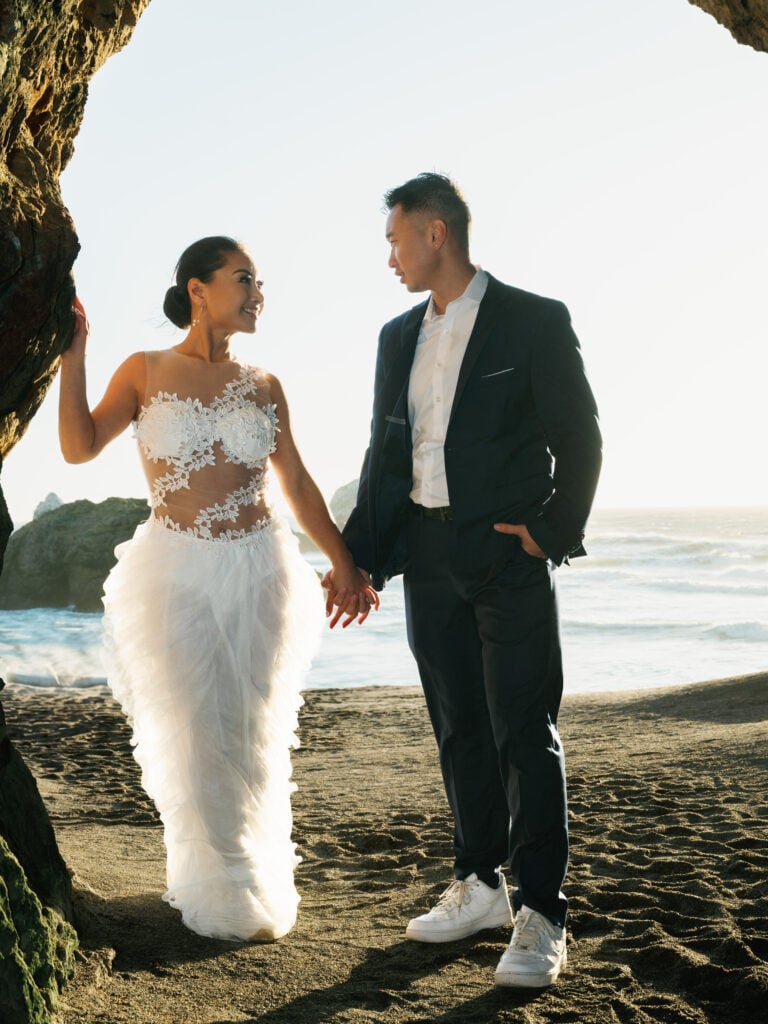 Editorial couple portrait on a rugged California beach, utilizing coastal light for high-fashion wedding venue photography.