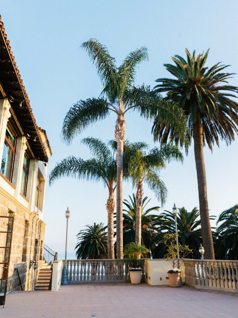 Sunset lighting over the elegant villa terrace and tall palm trees at Bel-Air Bay Club in Malibu.