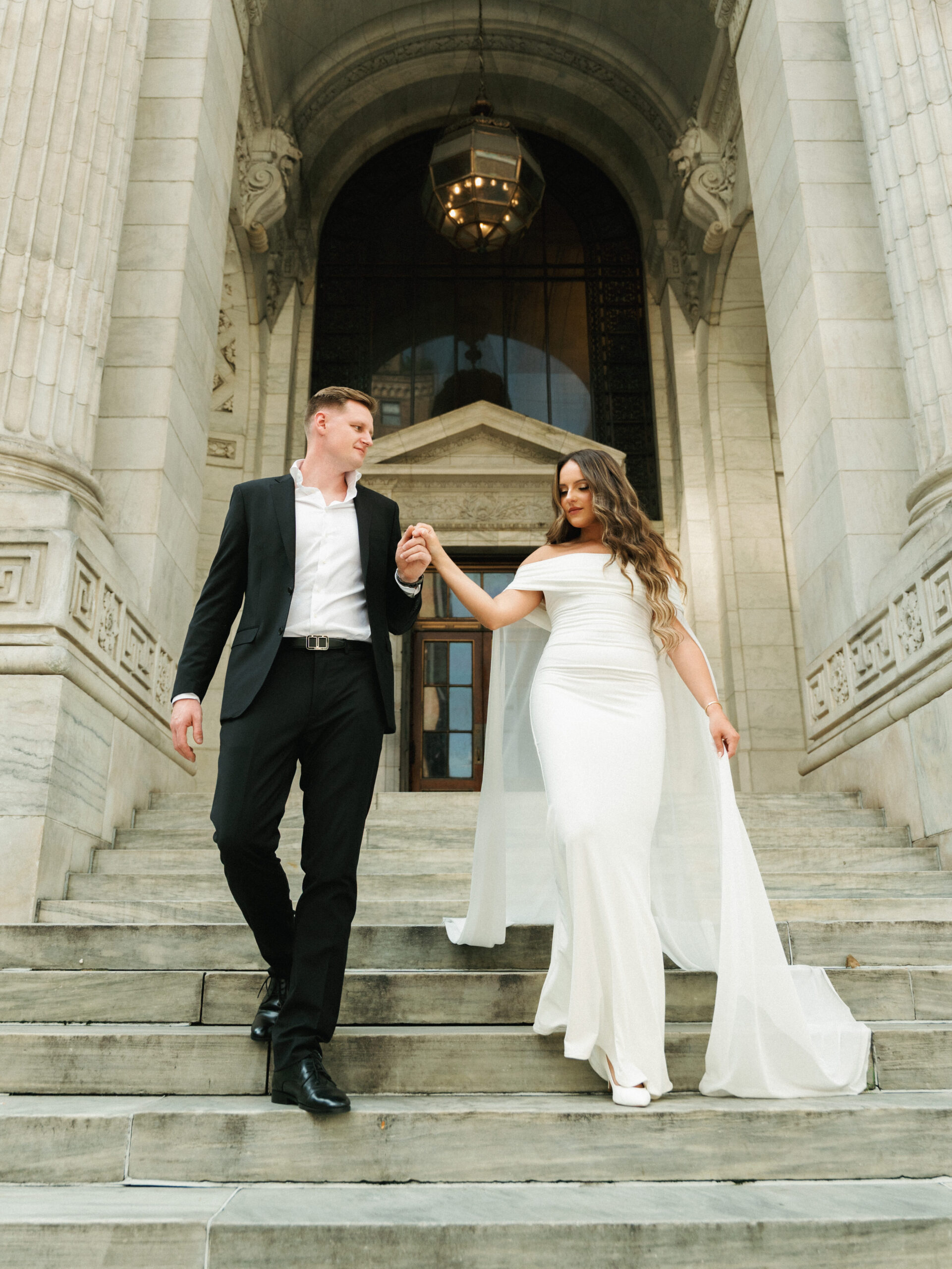 Cinematic wedding photo ideas of a luxury couple walking down iconic stone steps of a historic European-style building.