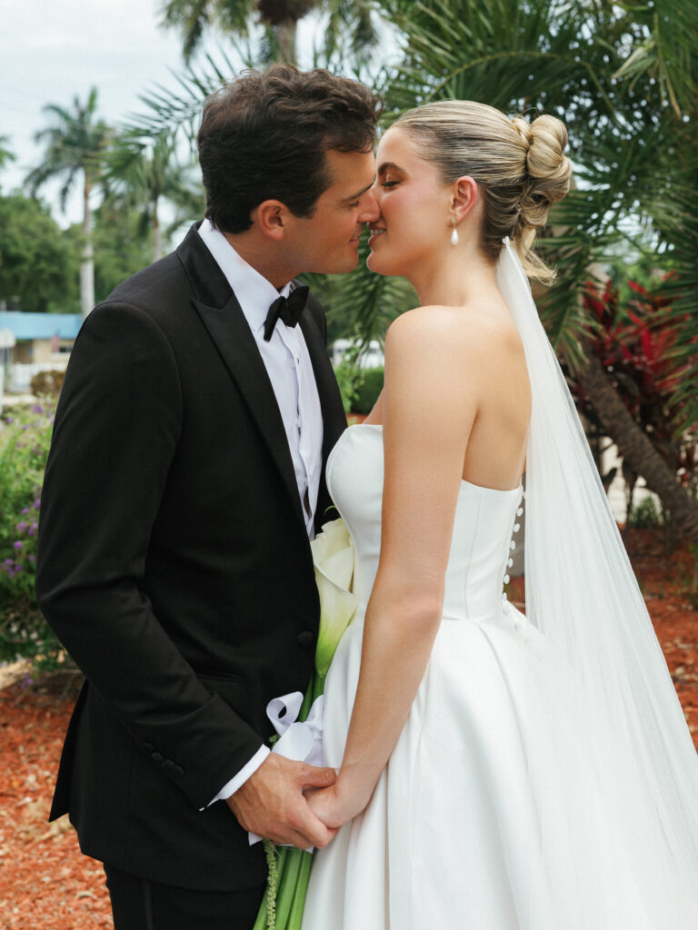 Romantic resort wedding photo ideas capturing an intimate close-up kiss between a black-tie groom and his bride.