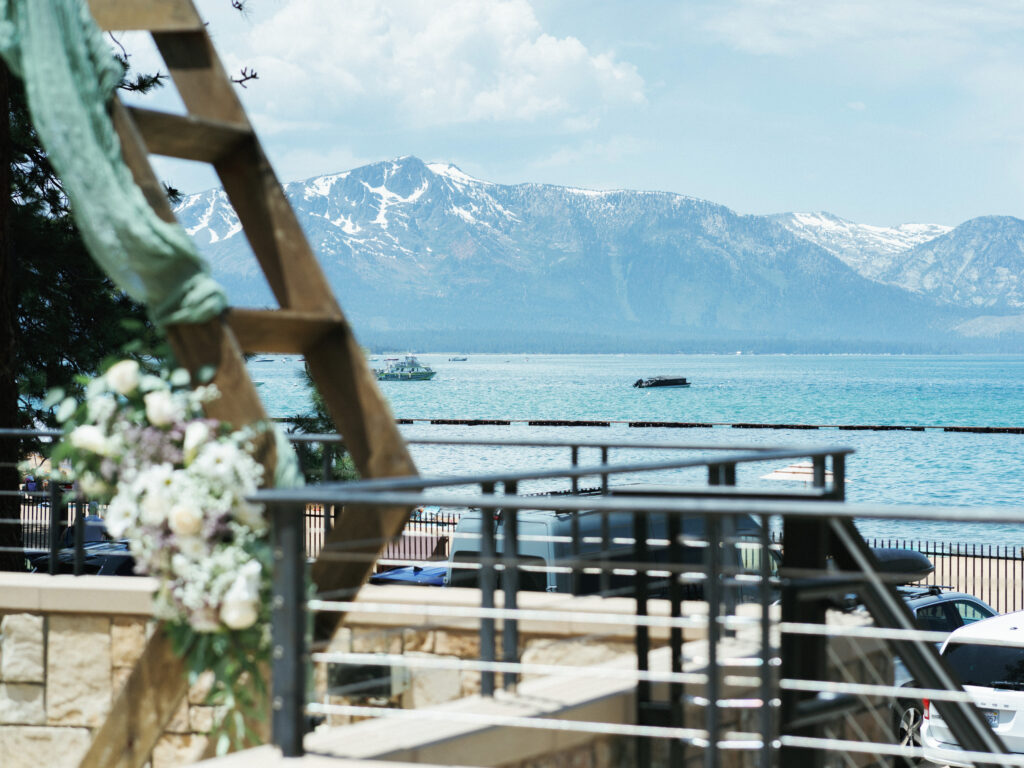 Panoramic view of turquoise Lake Tahoe and snow-capped Sierra Nevada mountains from a luxury wedding venue terrace.