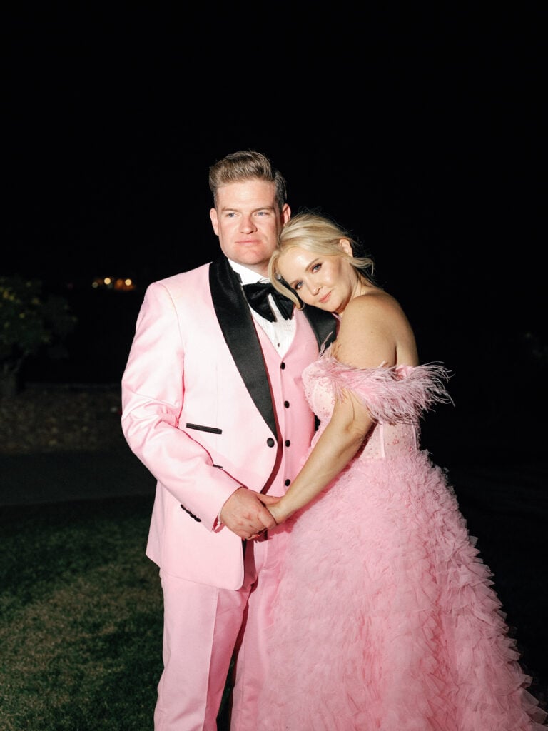 Bride and groom in matching pink wedding attire posing outdoors at night, captured on film by a Palm Springs wedding photographer.