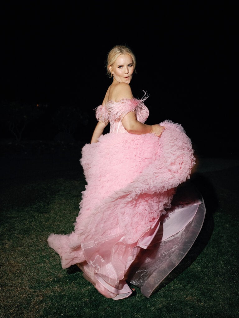 Bride twirling in a pink tulle wedding dress with feathers outdoors at night, captured on film by a Palm Springs wedding photographer.