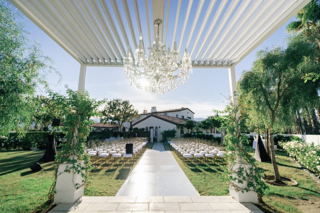 Sunny wedding ceremony setup at a Spanish-style desert villa with palm trees, taken on film by a Palm Springs wedding photographer.