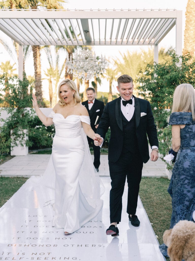 Bride and groom walking down a custom white wedding aisle runner after the ceremony, shot on film by a Palm Springs wedding photographer.