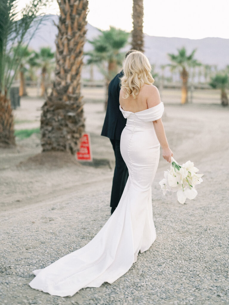Stunning bridal gown train showcased from behind on a desert estate path, shot on film by a Palm Springs wedding photographer.