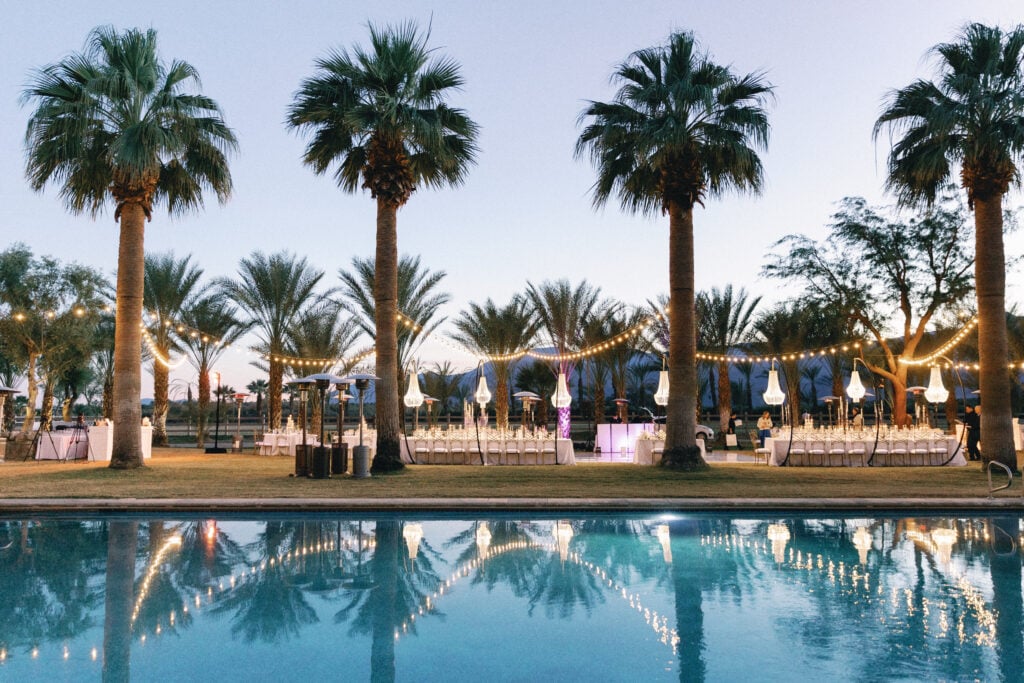 Poolside wedding dinner at a desert estate at dusk with palm trees reflection, taken on film by a Palm Springs wedding photographer.