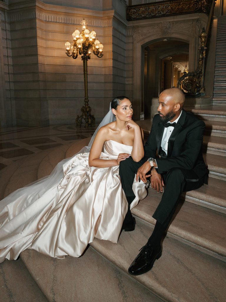 Cinematic wedding photo ideas featuring a luxury couple sitting on the grand staircase of San Francisco City Hall at night.