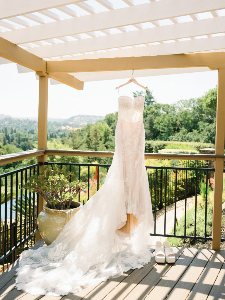 Stunning strapless wedding gown with a long train hanging on a wooden pergola, shot on film by a Napa Valley wedding photographer.
