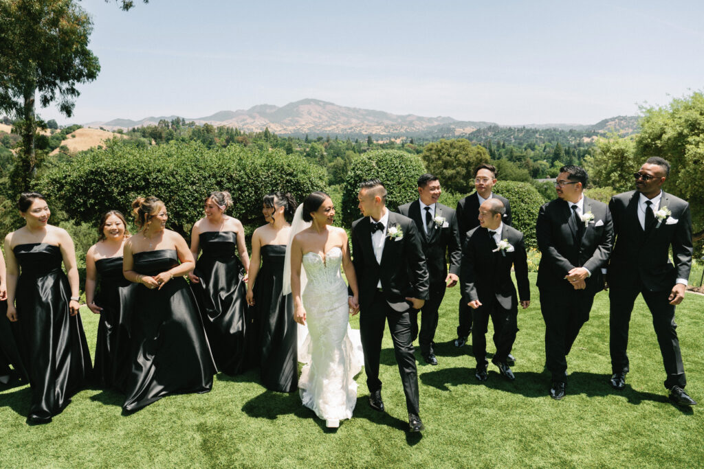 Modern black tie bridal party walking on a lawn captured on film by a Napa Valley wedding photographer.