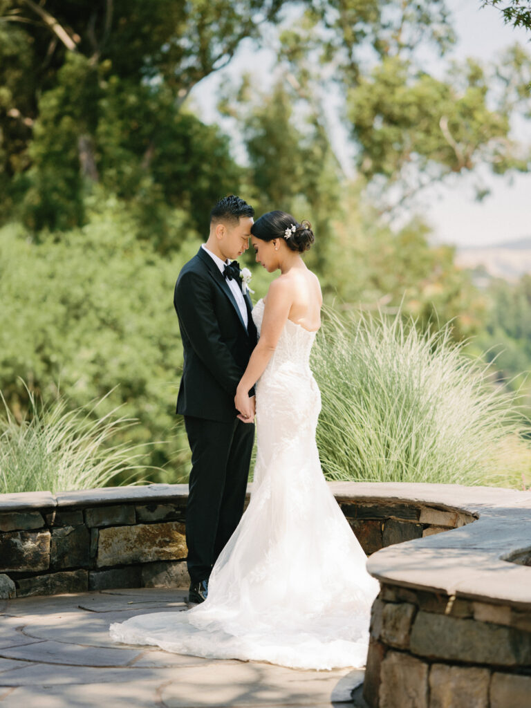 Intimate film wedding portrait of a couple holding hands on a stone terrace, curated by a professional Napa Valley wedding photographer.