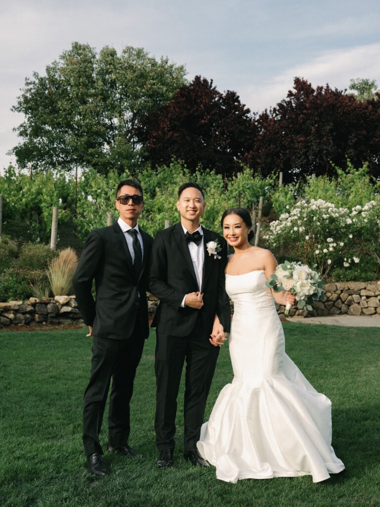 Chic film wedding photography of a couple posing with a groomsman on a lush lawn, captured by a professional Napa Valley wedding photographer.