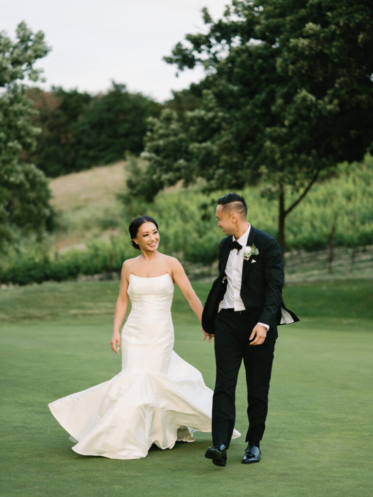 Candid film wedding portrait of a bride twirling in her mermaid dress while walking with her groom, captured by a Napa Valley wedding photographer.
