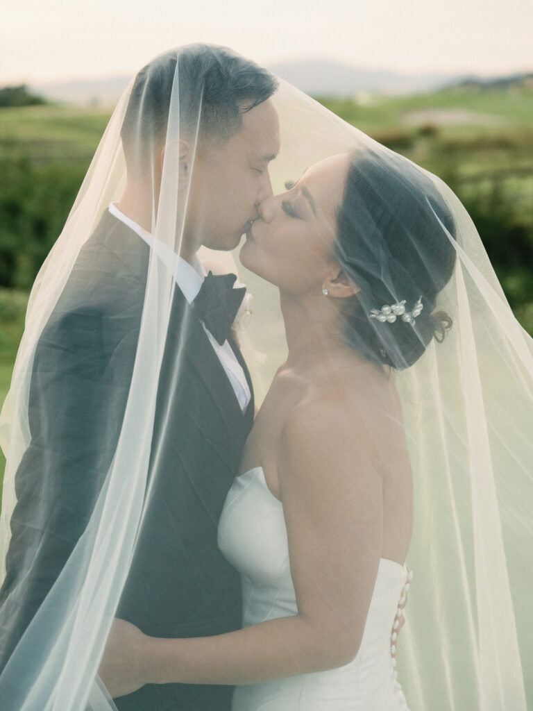 Intimate film wedding photography of a couple kissing under a sheer bridal veil, captured beautifully by a Napa Valley wedding photographer.