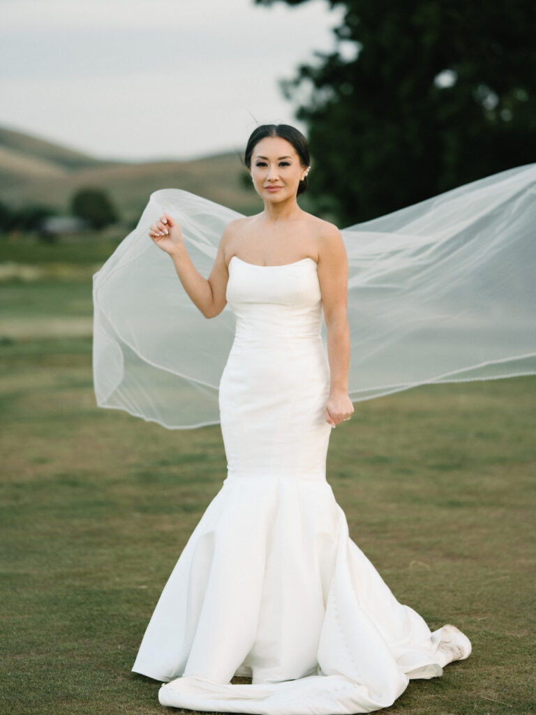 Chic bride in a strapless mermaid gown with a long flowing veil, shot on film by a Napa Valley wedding photographer.