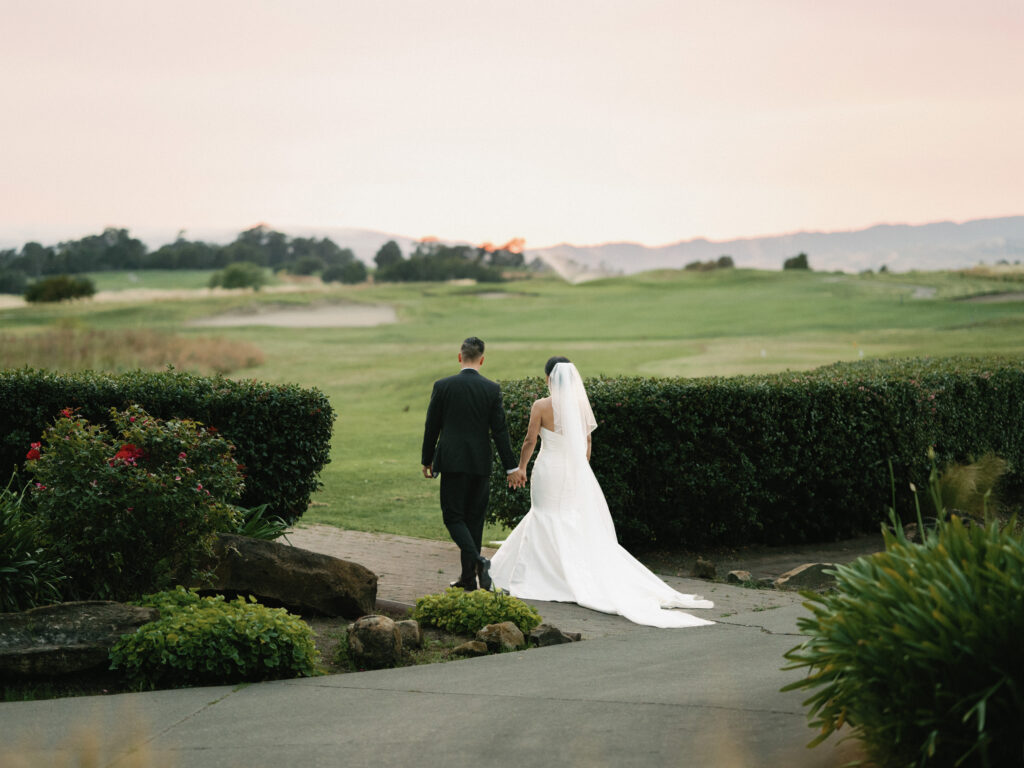 Romantic film wedding portrait of a couple strolling through a luxury estate at dusk, curated by a Napa Valley wedding photographer.
