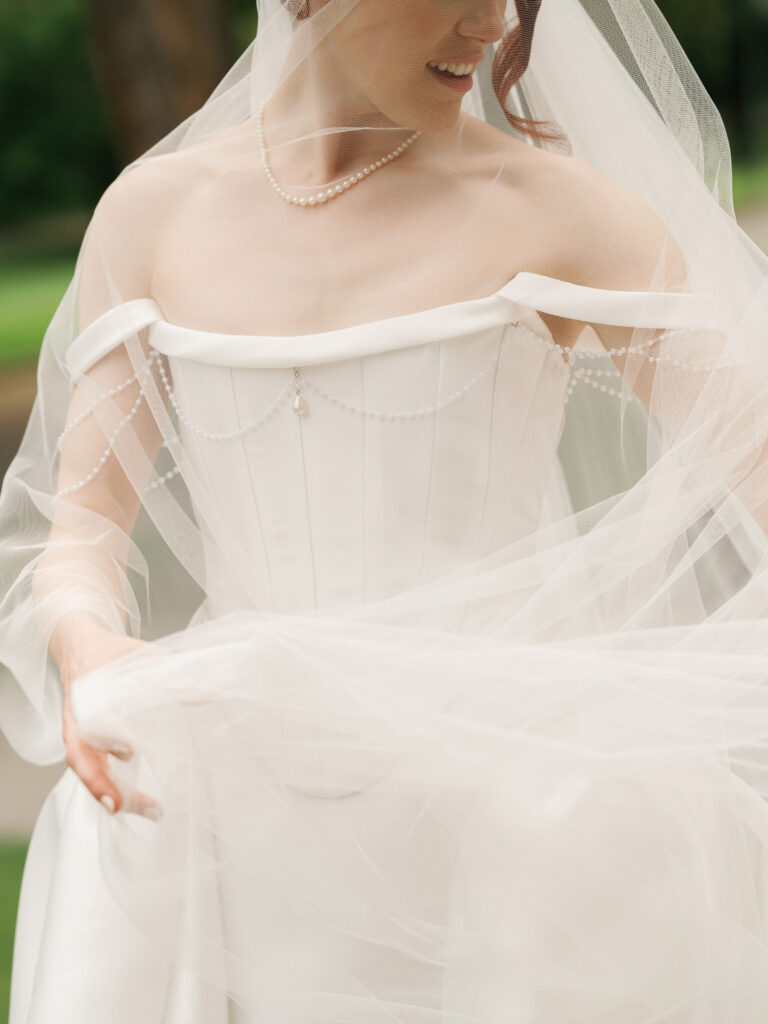 Detail-focused wedding photo ideas highlighting a luxury bride's corset gown with elegant pearl draping under a sheer veil.