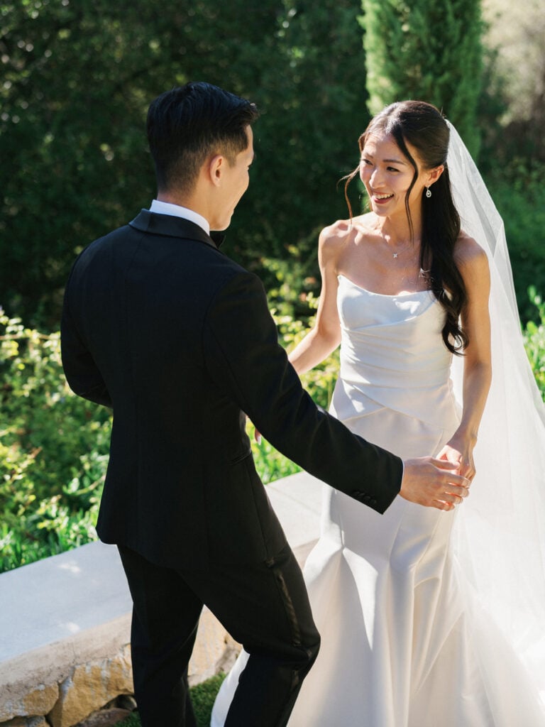 Joyful bride and groom holding hands during their emotional first look moment, showcasing elegant style inspiration for high-end destination wedding travel.