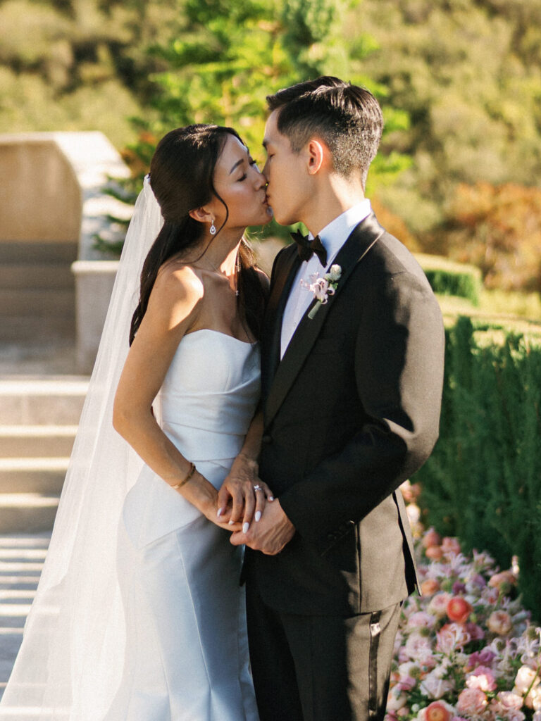 Classic bridal couple kissing during sunset portraits at a luxury vineyard estate, inspiring timeless outdoor wedding photo ideas.