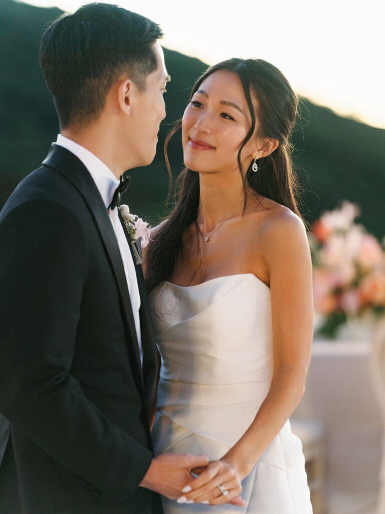 Elegant bride looking lovingly at her groom on a scenic outdoor terrace, offering modern editorial style inspiration for luxury destination wedding travel.