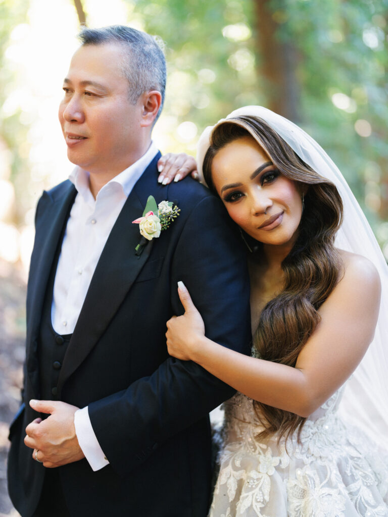 Bride leaning her head on grooms shoulder while holding his arm on a soft green background