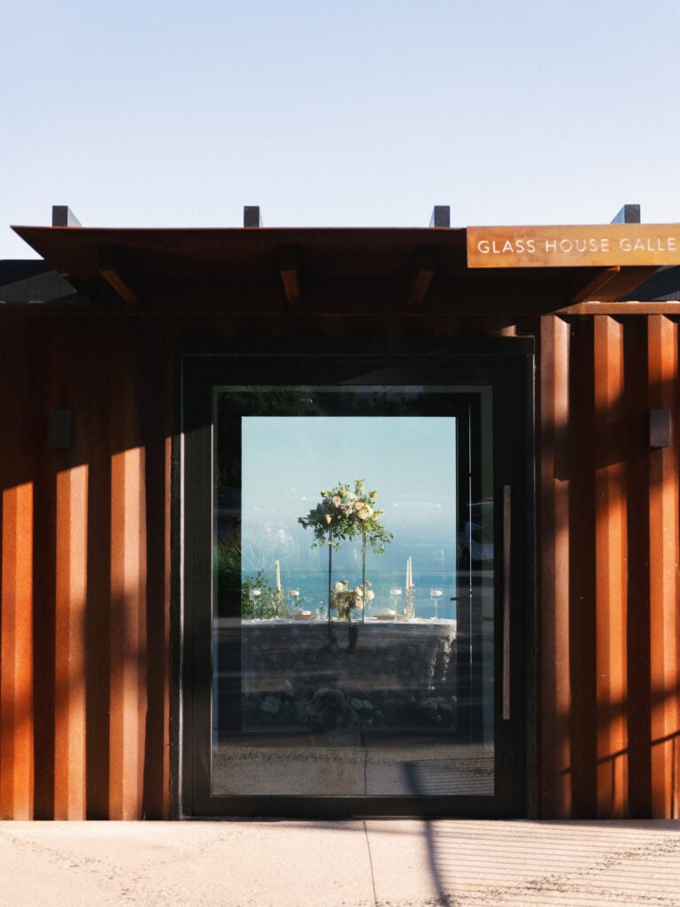 Corten steel facade of the Glass House Gallery wedding venue showcasing a large glass window looking into the reception dinner setup