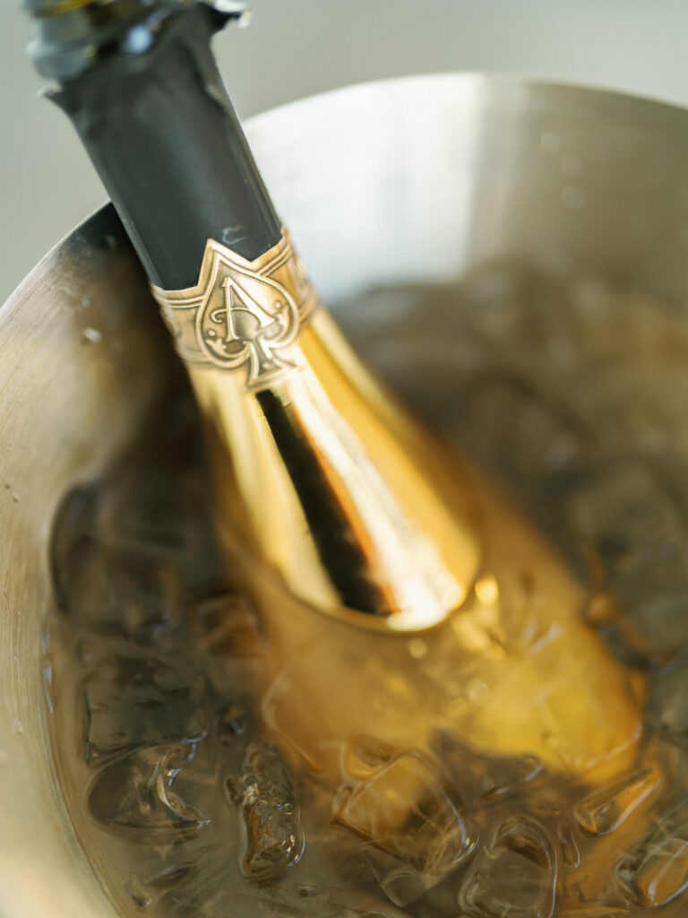 Gold bottle of Armand de Brignac Ace of Spades champagne chilling in a silver ice bucket captured by a Big Sur wedding photographer
