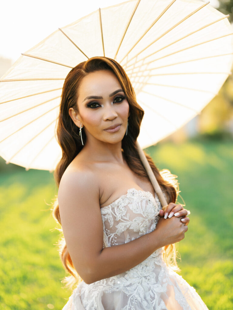 Close up portrait of a bride holding a white paper umbrella during a golden hour photoshoot captured by a Big Sur wedding photographer
