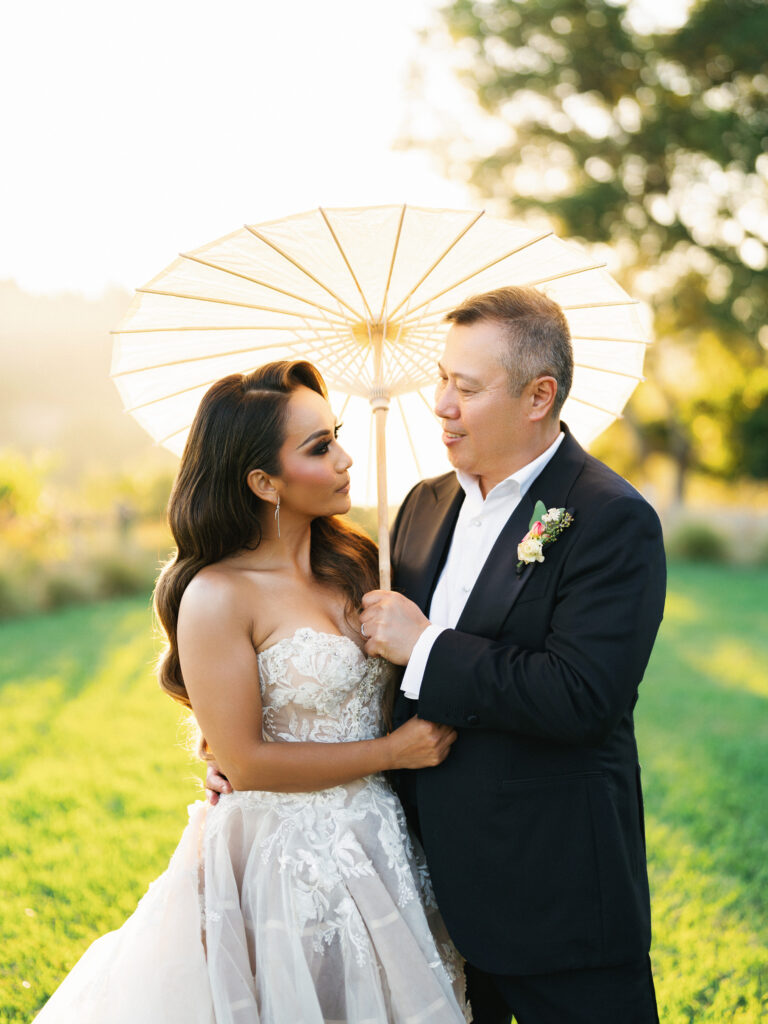 Bride and groom looking at each other while standing under a white paper parasol in Big Sur California