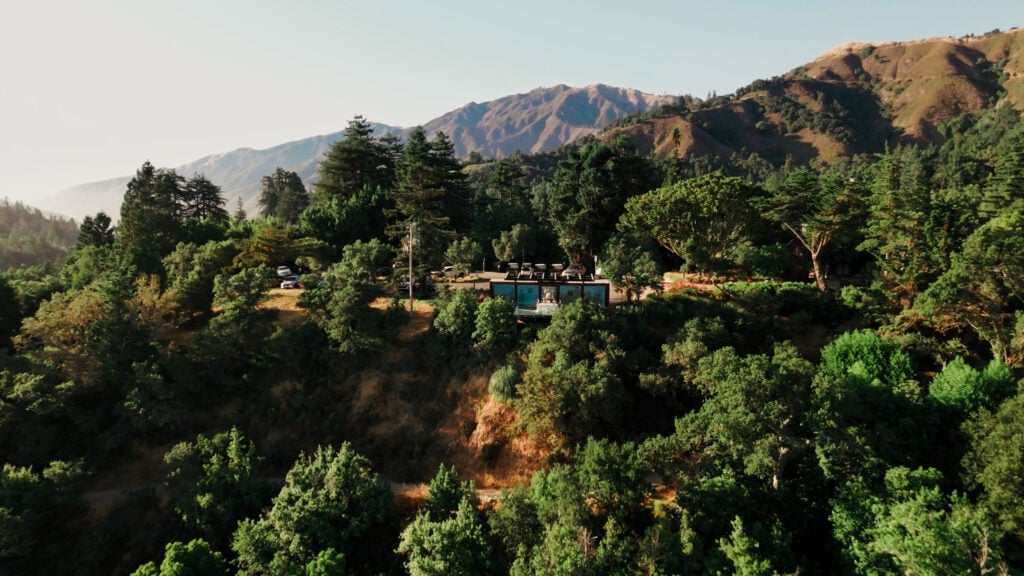Aerial view of a modern glass wedding venue tucked into the forested coastal hills of Big Sur California