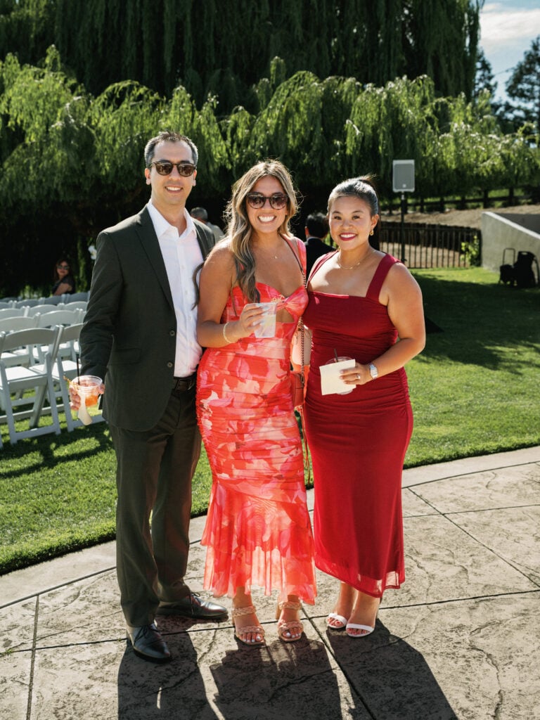 Sophisticated wedding guests in colorful cocktail attire posing on a sunny outdoor terrace, capturing the chic guest experience during professional wedding weekend coverage.