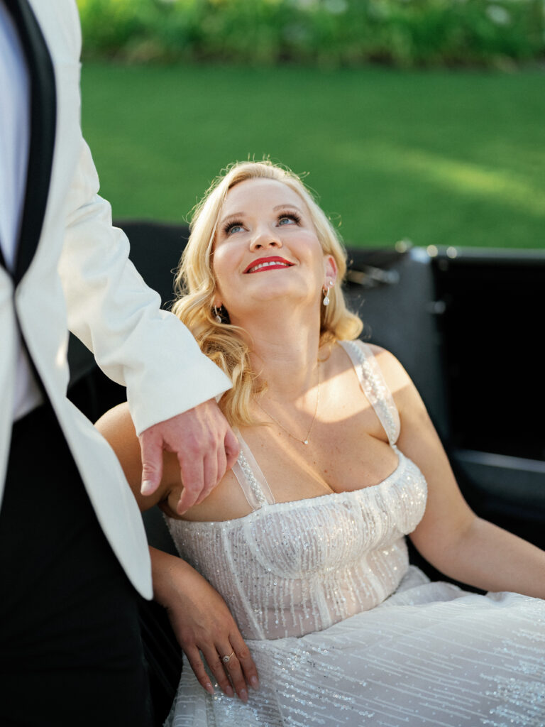 Candid film wedding portrait of a bride looking up from inside a classic convertible car, curated by a professional Palm Springs wedding photographer.