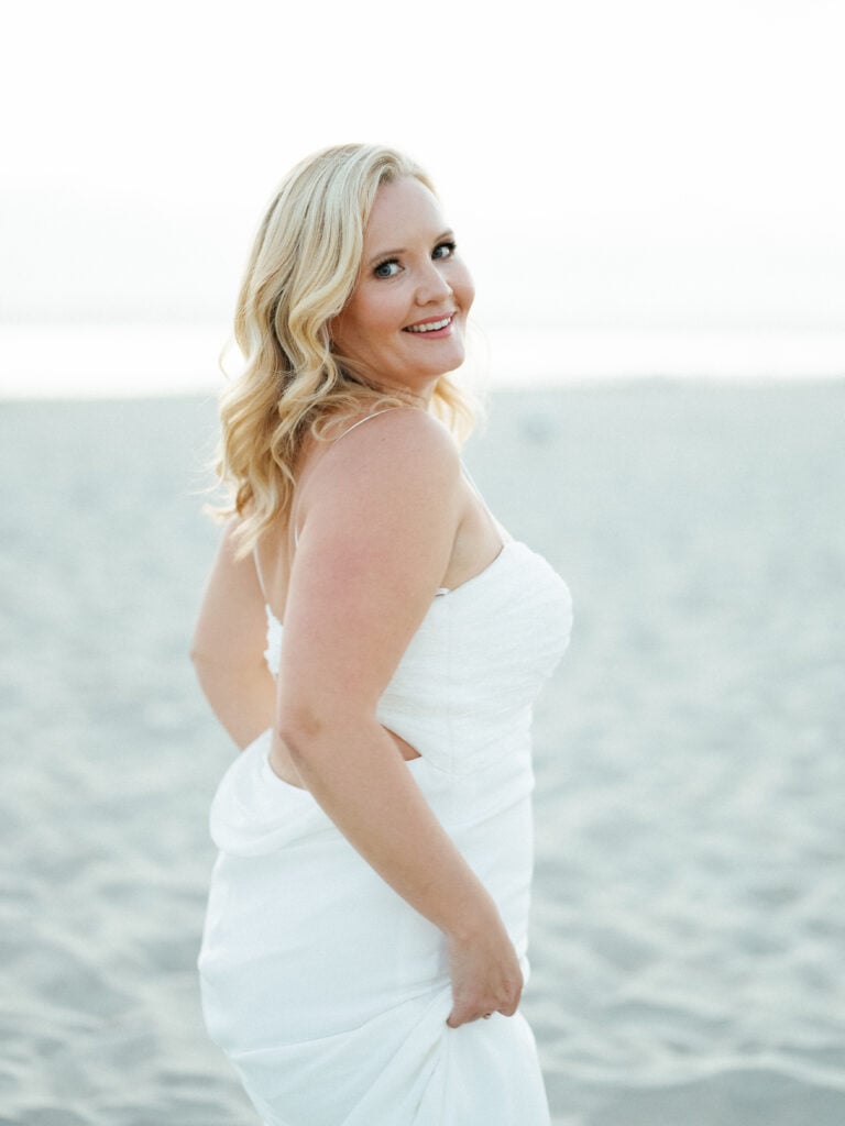 Bride in a white strapless gown looking over her shoulder on a sandy beach, shot on film by a Palm Springs wedding photographer.