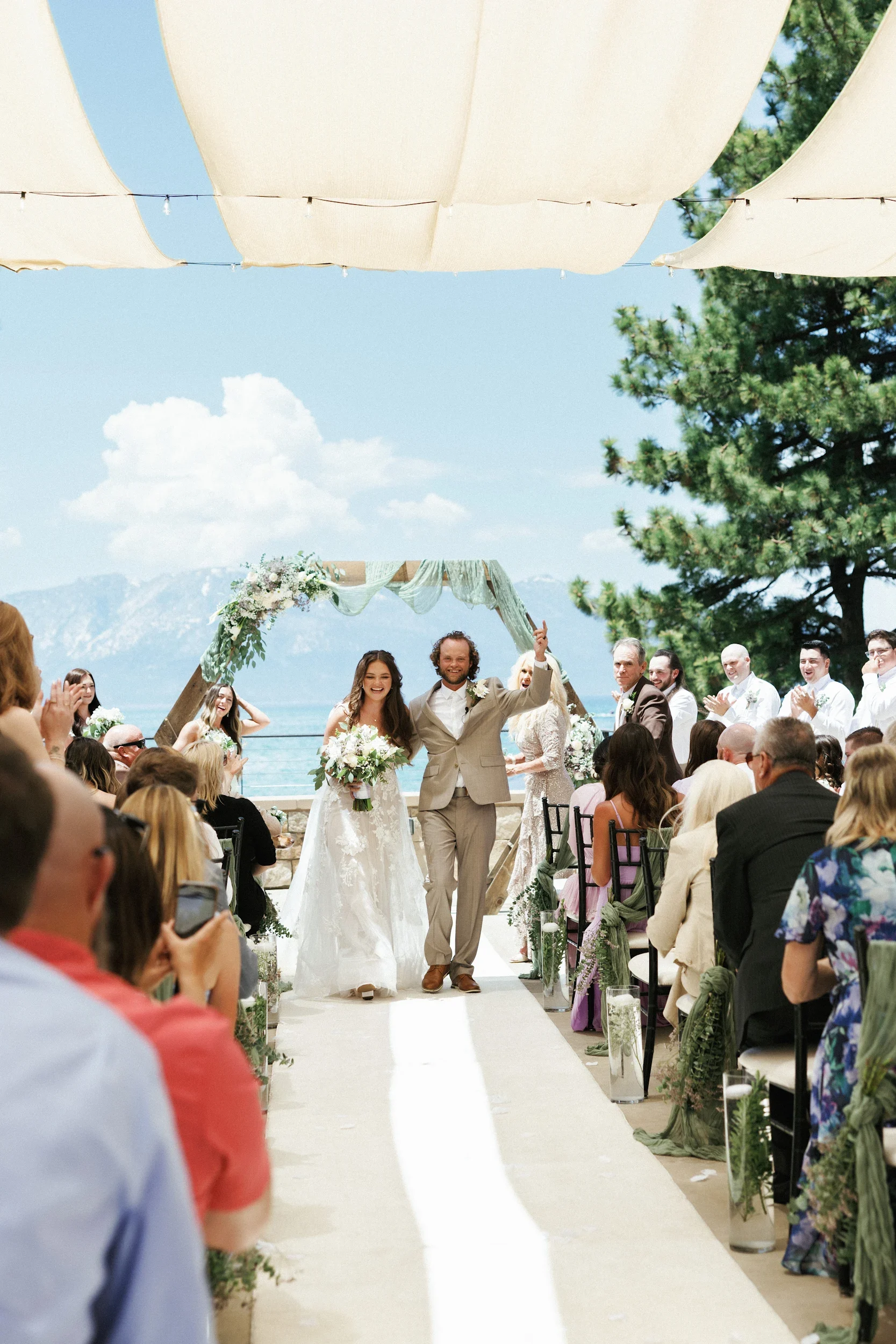 Outdoor wedding ceremony lake tahoe with newlyweds walking down the aisle under a fabric canopy canopy