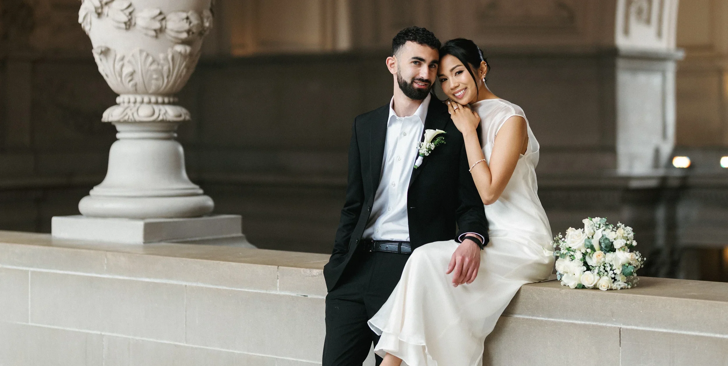 Romantic fine-art wedding photo ideas featuring a bride leaning on her groom's shoulder inside San Francisco City Hall.