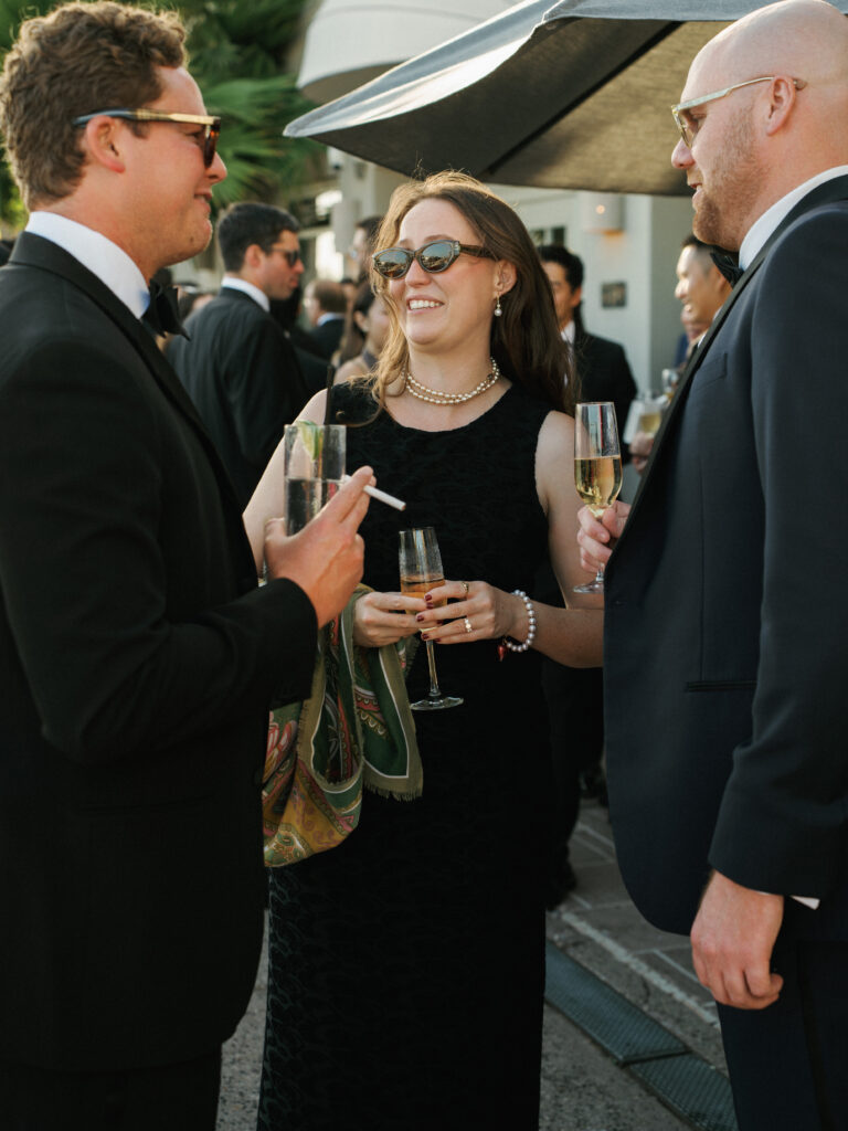 Chic outdoor wedding cocktail hour guest style with black dresses and classic black tuxedos