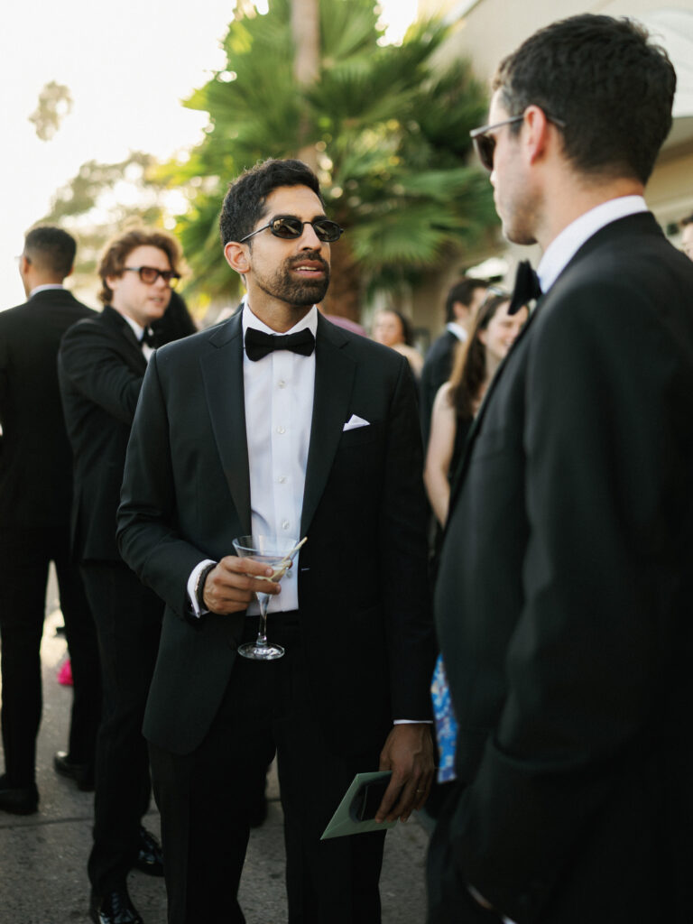 Groomsmen in elegant black tie attire holding martini glasses before the wedding reception toasts speeches begin