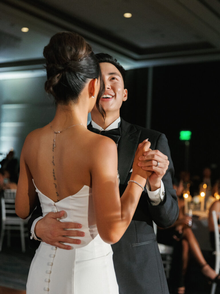 Sleek bridal updo and strapless wedding dress with back jewelry details captured during the wedding first dance